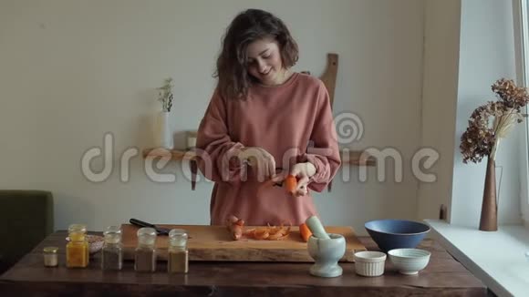 可爱的小女孩把胡萝卜皮放在木板上在厨房里用香料切菜视频的预览图
