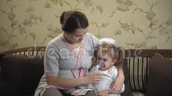 小女孩坐在沙发上用压缩机吸入器吸入一个怀孕的孩子视频的预览图
