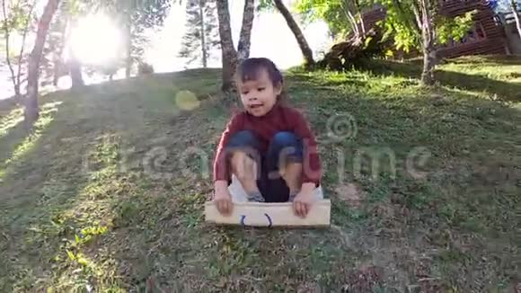可爱的小女孩在一个夏天的公园里玩滑梯在斜坡上玩回收纸板箱幸福的概念视频的预览图