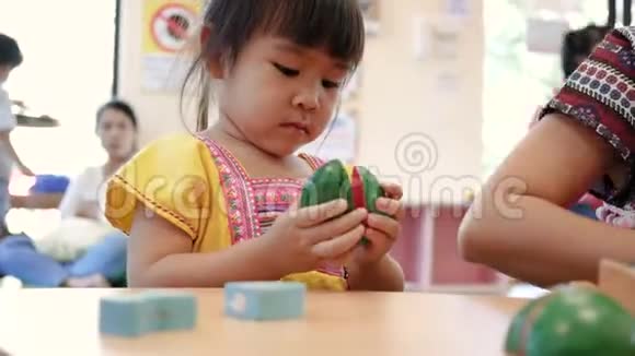 可爱的小女孩在教室的客厅玩烹饪玩具小孩用木头玩具刀切植物视频的预览图