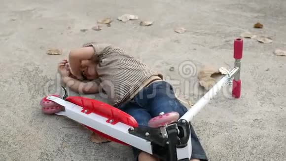 可爱的亚洲小女孩躺在地上后从她的滑板车在夏季公园幼儿健康户外运动视频的预览图