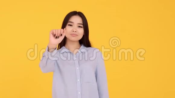 女孩亚洲女孩在黄色背景上挥手告别空中亲吻视频的预览图