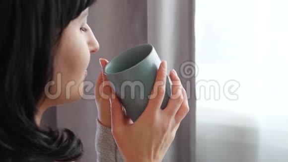 女孩喜欢喝热茶或咖啡看着窗外一个女人脸侧写视频的预览图