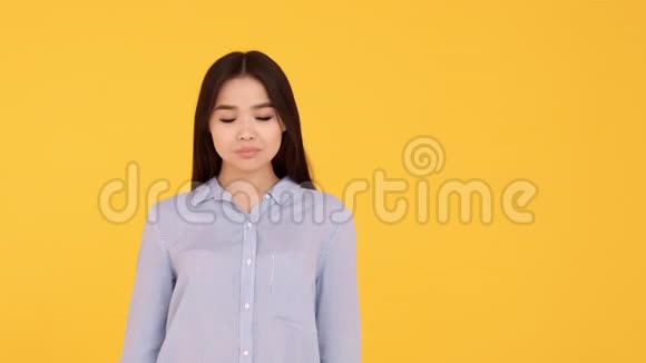 黄色背景的亚洲女孩展示了和平和微笑的姿态视频的预览图