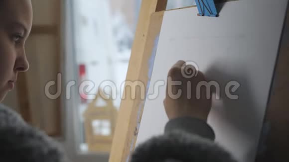 艺术工作室的一个十几岁的女孩在画架上画板笔的轮廓特写视频的预览图