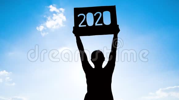 女人拿着回收纸板的剪影用2020年的文字在蓝天背景和阳光下通过文本概念视频的预览图