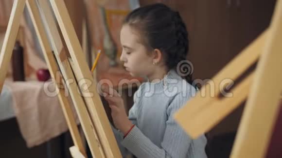 那个女孩坐在画架上画艺术工作室视频的预览图