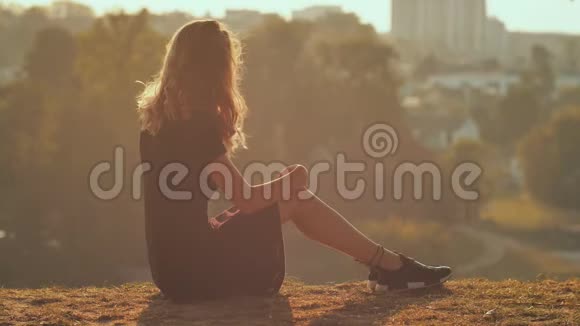 悲伤的女孩剪影独自坐在草地上如此孤独和哭泣视频的预览图