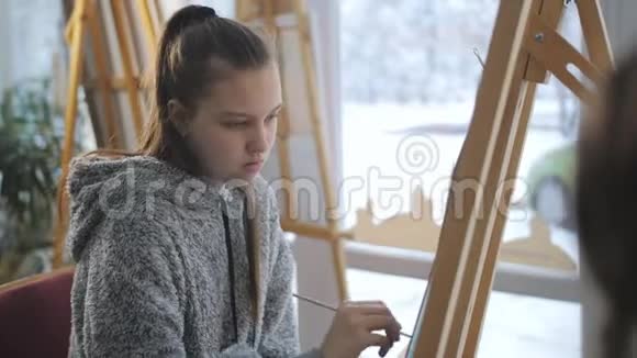 一个拿着铅笔的少女在艺术学校里坐在画架上画着静物视频的预览图