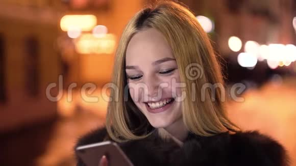 女人在冬天晚上使用智能手机微笑视频的预览图