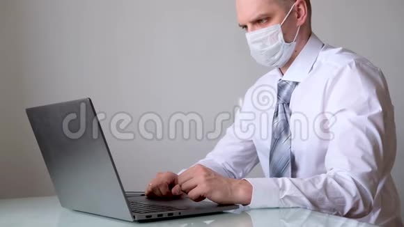 穿着医用口罩和办公室服装白衬衫和领带的人在笔记本电脑上远程从家里谈生意关于视频的预览图