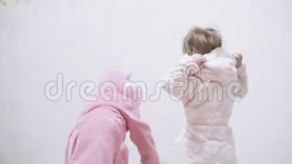 两个孩子穿着浴袍在一个白色背景和湿发后洗澡在白色床上洗澡后的男孩和女孩视频的预览图