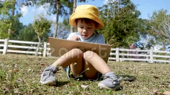 艺术家小女孩坐在一个夏天公园的回收纸板箱上画画视频的预览图
