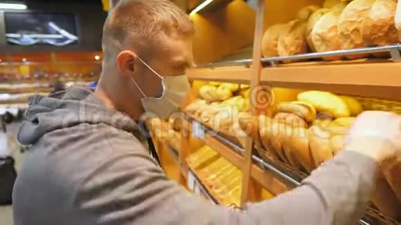 带医用口罩的年轻人在超市里选择了一条新鲜的面包在生产部挑选食物的人视频的预览图