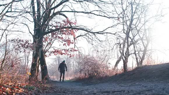 秋天一个男人在阳光明媚的天气里在城市公园散步视频的预览图