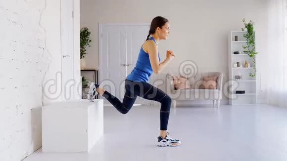 漂亮的女孩在一条腿上表演一个分开的蹲她在家做运动视频的预览图