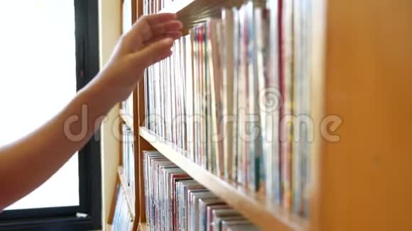 女人在图书馆书架上找书拿一本书读教育活动和生活方式概念视频的预览图