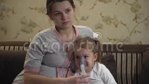 小女孩坐在沙发上用压缩机吸入器吸入一个怀孕的孩子视频的预览图