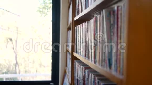 女人在图书馆书架上找书拿一本书读教育活动和生活方式概念视频的预览图