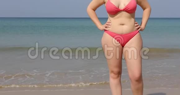 穿着粉色比基尼站在沙滩旁的女人视频的预览图