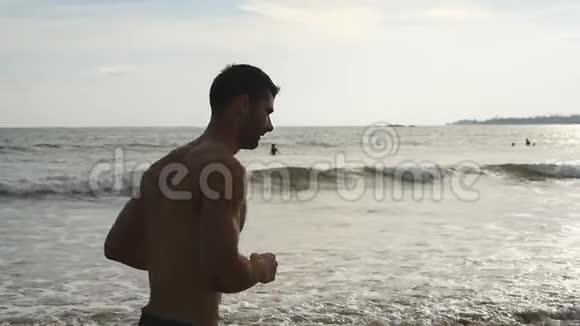年轻的运动健将沿着海岸奔跑运动帅哥在美丽的海景背景下慢跑男运动员视频的预览图