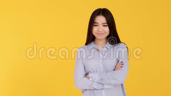 黄色背景的年轻亚洲女孩微笑着看着相机蓝色衬衫视频的预览图
