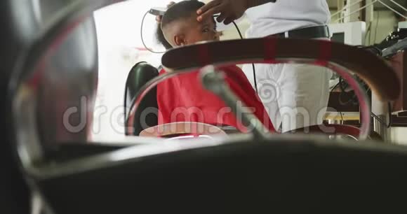 非洲男子剪非洲男孩头发的远观视频的预览图