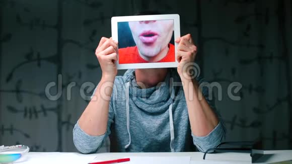 一个人手里拿着一块平板电脑在平板电脑屏幕上特写他的嘴唇视频的预览图