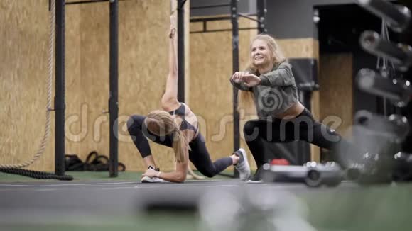 年轻女性一起在健身房健身中心训练伸展腿部肌肉集体锻炼视频的预览图