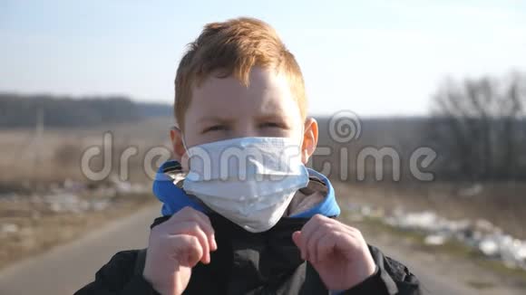带着医用口罩的小男孩站在户外的肖像快乐的男孩子从病毒和视频的预览图