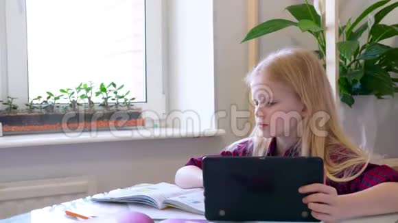 远程学习在线教育女学生在家里用数字平板电脑学习做学校作业培训视频的预览图