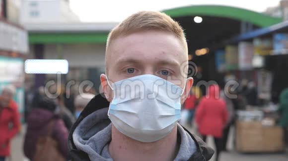 戴着医用口罩的年轻人的肖像立在城市街道上快乐的人从病毒和视频的预览图