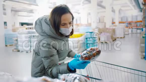 一个女人带着一个女儿穿着冬天的衣服脸上戴着医用口罩在一家商店里买了杏干干果视频的预览图