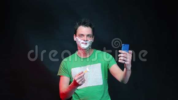 一个男人在看智能手机的时候会自己刮胡子视频的预览图