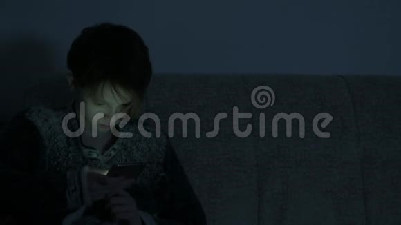 十几岁的女孩在黑暗的房间里使用智能手机视频的预览图