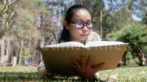 夏天亚洲年轻女子坐在公园里放松和看书活动和生活方式理念视频的预览图