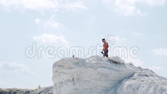 健身者在蓝天背景下的白山上喝一瓶水视频的预览图