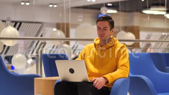 年轻自信的忙碌的男人坐在咖啡馆里用笔记本电脑工作视频的预览图