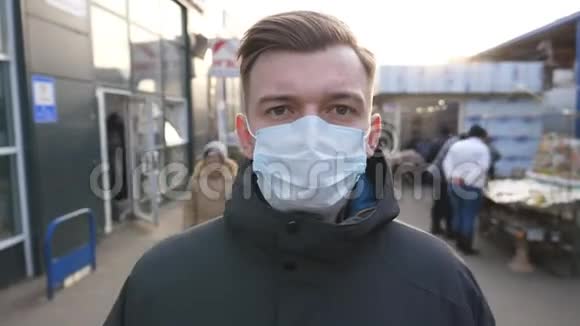 戴着医用口罩的年轻人的肖像立在城市街道上在户外戴防病毒面具的人视频的预览图