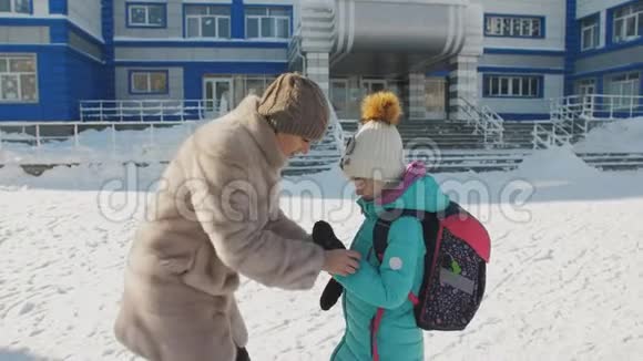 在学校门口的母女在冬天道别母亲纠正女儿衣服视频的预览图