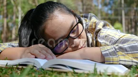 亚洲年轻女子放松和阅读一本书躺在公园的夏天活动和生活方式理念视频的预览图
