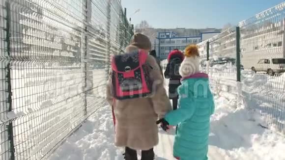 妈妈和小女儿在冬天一起上学妈妈把女儿背包放在他肩上视频的预览图
