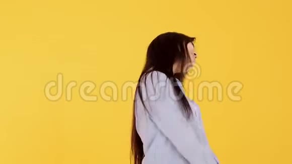 亚洲女孩在一个黄色背景的女人看着镜头时笑容满面视频的预览图