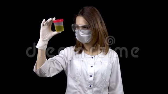 一位年轻的女医生正在检查尿液测试一个女人在黑色背景上检查一个装有尿液的测试罐视频的预览图