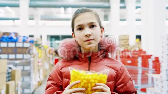一个穿着超市冬装的小女孩手里拿着一包黄色的窗帘视频的预览图