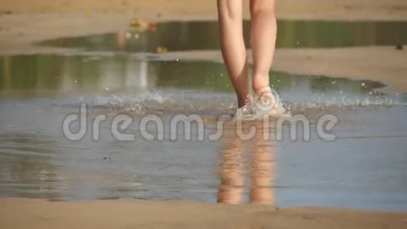 低视野的女性腿进入大水坑附近的海滨年轻女子光着脚空着走视频的预览图
