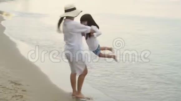 快乐的亚洲家庭与母亲放松携带和旋转女儿一起度假在海滩视频的预览图