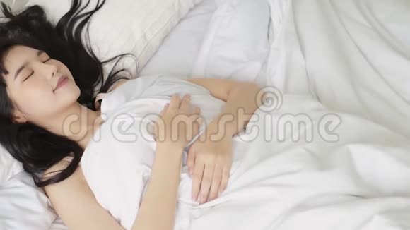 美丽的年轻亚洲女人早上醒来在卧室的床上开心地打哈欠视频的预览图