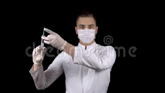 年轻的医生正拿着装满药物的注射器站着一位医生从注射器里喷出来以释放空气视频的预览图