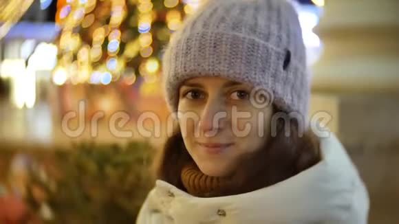冬天美丽的年轻女子在户外圣诞灯光背景下的画像视频的预览图